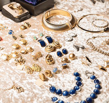 Goldfarbener Modeschmuck mit Ohrringen, Armreif und blauer Perlenkette